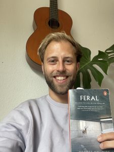 Man holding the book feral by George Monbiot in the camera.