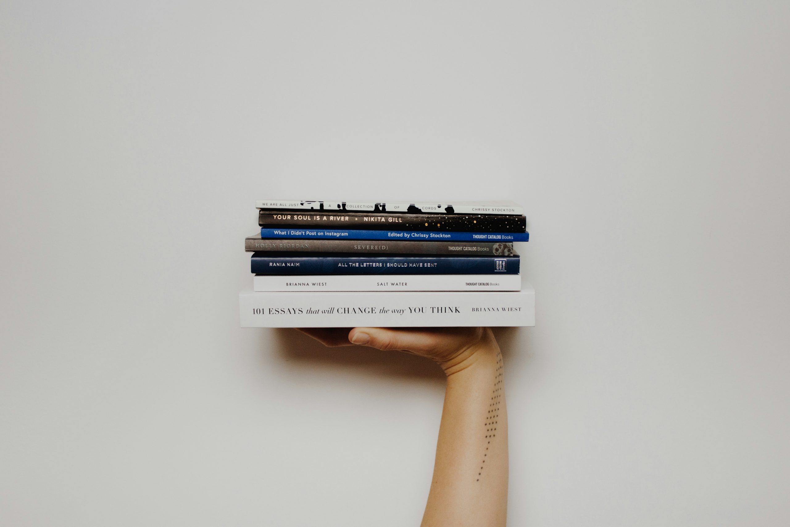 Pile of books on a hand before a white background.