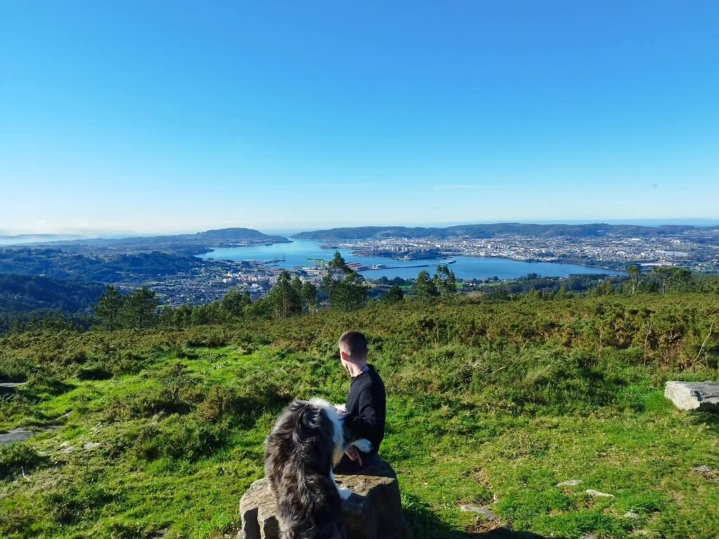 guy sitting on rock with dog looking over a river