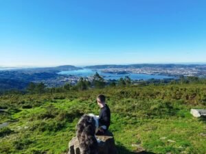 guy sitting on rock with dog looking over a river